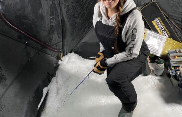 Rene kneeling with an ice rod while fishing through the ice